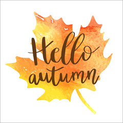 Wall Mural - Hello autumn hand lettering phrase on orange watercolor maple leaf background.