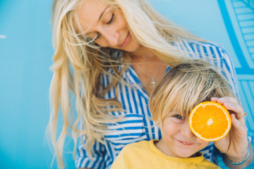 Woman covering eyes of toddler cute boy with orange