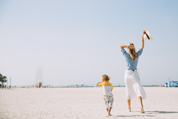 Young mother and happy little son at sandy beach in Dubai, UAE