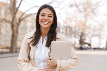 Canvas Print - Happy brunette woman in jacket holding laptop computer