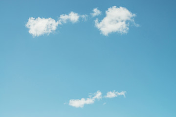 Wall Mural - several white fluffy beautiful clouds swim in clear blue sky in daylight. background image of day sk