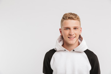 Portrait closeup of teenage boy 16-18 years old wearing hoodie looking at camera with happy smile, isolated over white background