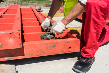 Wall Mural - Low-angle view of a serious blue-collar worker installing metallic framing while working at the foundation of a building under construction