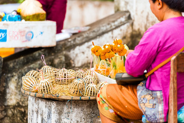 Wall Mural - Woman sells sacrifices from the leaves of bananas and flowers, Luang Prabang, Laos. Close-up.