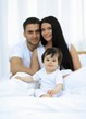 © ASDF - Portrait of a joyful family sitting on the bed at home