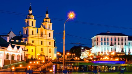 Wall Mural - Minsk, Belarus. Aerial view of Cathedral with people and car traffic in Minsk, Belarus. Car trail lights and purple sky. Time-lapse of a sunset, zoom in