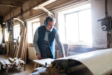 Wall Mural - A man worker in the carpentry workshop, working with wood.