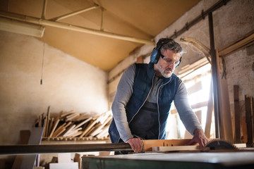 Wall Mural - A man worker in the carpentry workshop, working with wood.