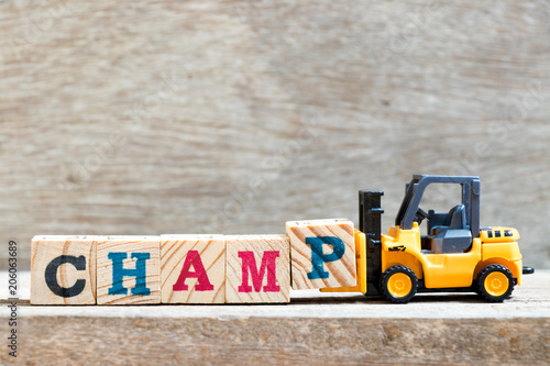 Fotografie, Obraz Toy forklift hold letter block P to complete word champ on wood background