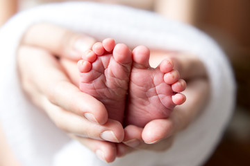 feet newborn baby in a white cloth in my mother's hands