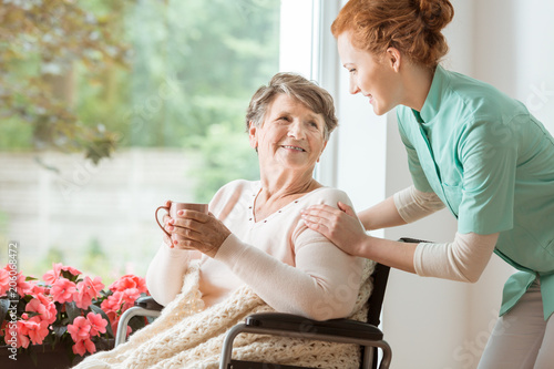 Fotografía A professional caretaker in uniform helping a geriatric female patient on a wheelchair