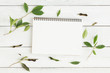 © sorrapongs - Flat lay photo of blank whtie notebook and green leaf on whtie table
