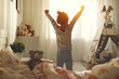 © JenkoAtaman - child girl wakes up  and stretches in morning in bed and stretches