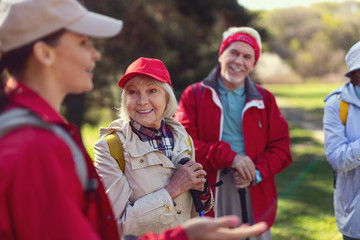 Lovely guide. Content blond woman smiling and listening to the guide while hiking