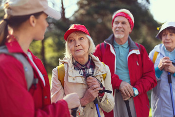 attention. concentrated blond woman smiling and listening to the guide while hiking