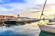 Luxury yachts and motor boats at sunset. Sailing boats docked at pier in marina in sunshine.