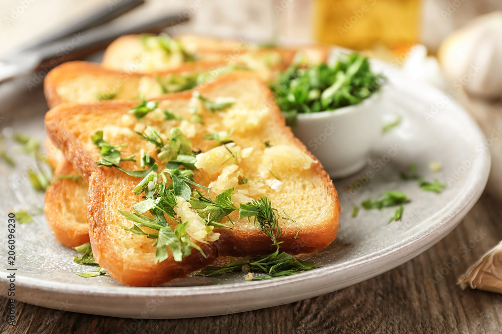 Plate with delicious homemade garlic bread on table