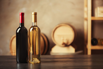 Canvas Print - Bottles of delicious wine and blurred barrels on background