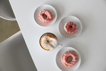 Coffee And Pink Glazed Donuts On Table