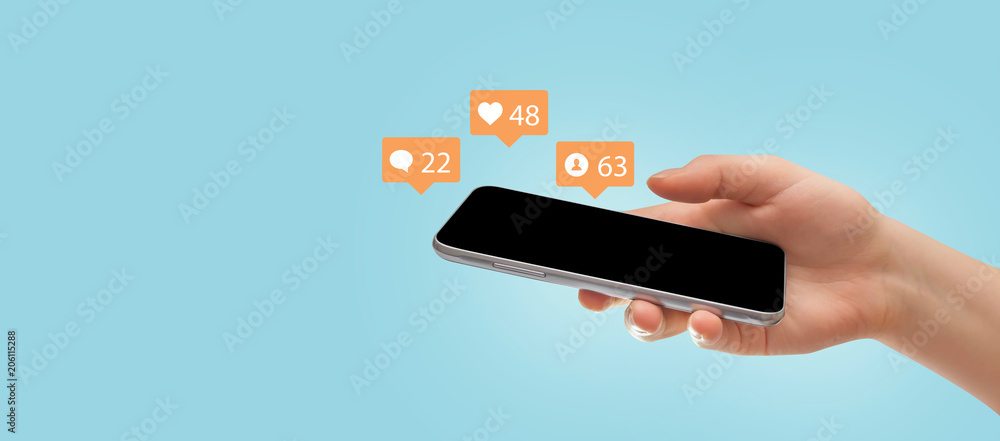 Female hand holding smartphone, surrounded with social media icons on blue background. Social media concept - obrazy, fototapety, plakaty 