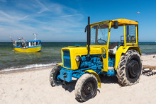 Old Tractor On The Beach And Fishing Boat On The Sea