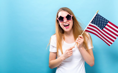 Wall Mural - Happy young woman holding an American flag on a blue background