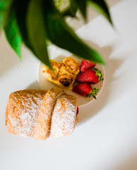 Bread with strawberries and cheese in the form of a heart is decorated with green leaves