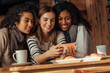 © Jacob Lund - Friends at a cafe looking at mobile phone