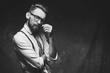 © berezko - Young stylish hipster with cool hairstyle and beard dressed in white shirt and suspenders is thinking of a new creative idea looking at viewer