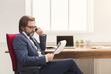 Serious businessman talking on smartphone at office