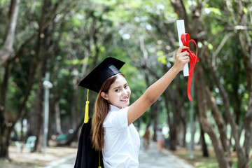 Beautiful Attractive Graduate in graduation cap put her hand up and celebrating with certificate in her hand in Commencement day so proud and happiness,Education success Concept