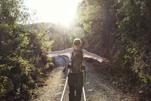 Greece, Pilion, Milies, Back View Of Man With Backpack Balancing Along Rails Of Narrow Gauge Railway
