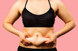 © vika33 - Body of young woman with excess weight, keeping your belly fat, isolated on pink background.
