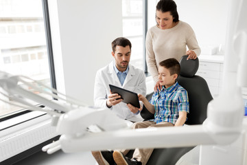 Canvas Print - medicine, dentistry and healthcare concept - dentist showing tablet pc computer to kid patient and his mother at dental clinic