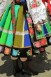 Tradycyjna pasiasty ludowy strój kobiety z Łowicza, widoczna kobieta od pasa w dół, pasiasta kolorowa wyszywany w kwiaty wełniana spódnica, biała koronkowa koszula, zapaska, dłoń, na ulicy