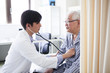 © Monet - 医療用ベッドで医師の診断を受ける高齢者の男性。