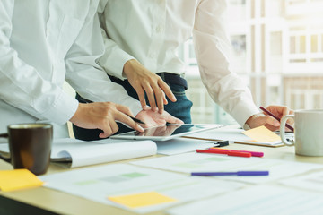 Two Business colleagues standing around boardroom table having informal discussion a new start up project.	