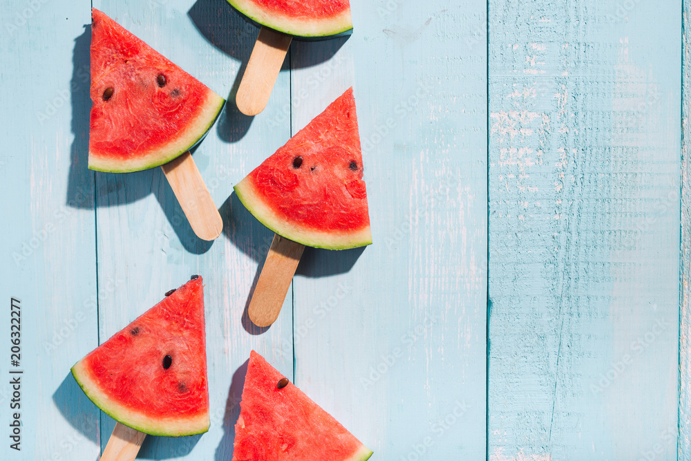 Slices of watermelon on blue wooden desk. - obrazy, fototapety, plakaty 