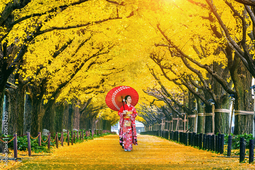 Fotografía Beautiful girl wearing japanese traditional kimono at row of yellow ginkgo tree in autumn