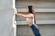 © Dirima - Sporty young woman doing standing wall push up triceps strength exercise during urban outdoor fitness workout.