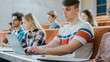 © Gorodenkoff - Handsome Caucasian Student Uses Laptop while Listening to a Lecture at the University. Multi Ethnic Group of Modern Bright Students Invested in Their Future.
