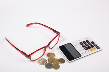 finance concept: calculator, glasses and coins isolated on white background