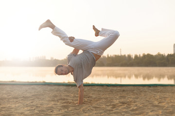 Wall Mural - Athletic capoeira performer workout training on the beach sunris