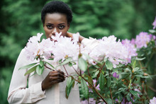 Portrait Of Young Afro American Woman Surrounded Purple Flowers In Park