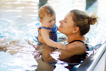 Wall Mural - Happy mother swimming with cute adorable baby girl daughter in swimming pool spending spa vacations