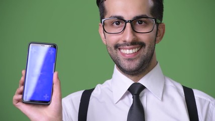 Wall Mural - Young handsome bearded Persian businessman against green background