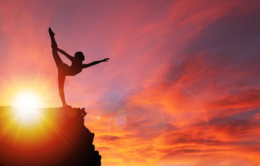 Silhouette of Girl Exercising on Edge of Cliff at Sunrise