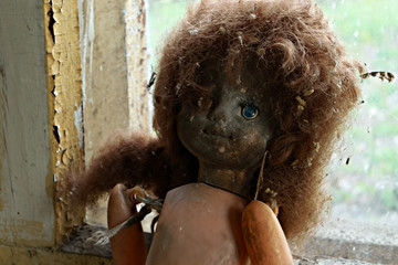 Creepy doll sitting on windowsill in abandoned kindergarten in city Pripyat after Chernobyl disaster