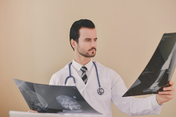 Wall Mural - Smiling doctor posing in the office, he is wearing a stethoscope, medical staff on the hospital background