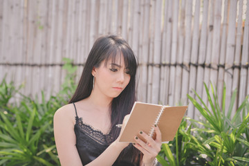 Education Concepts. Asian women reading books in the park. Beautiful women are relaxing in the park. Beautiful women are happy to read.